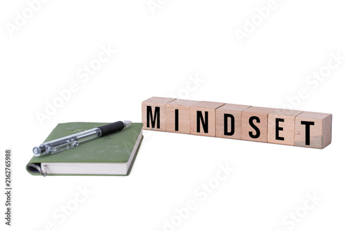 MINDSET word written on wooden blocks next to a green notebook and pen isolated on white