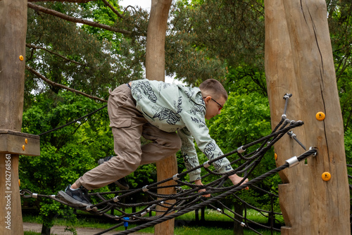 Canvastavla Focused boy crawling across complex rope obstacle at adventure playground in park