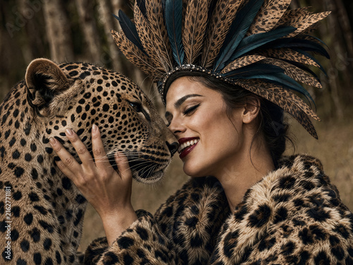 Smiling woman embracing leopard in high fashion forest portrait