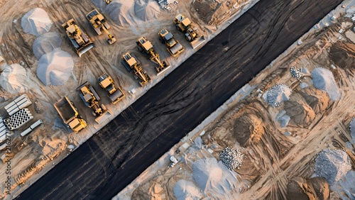 Aerial view of heavy construction machinery parked at a road building site.