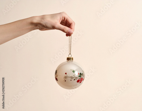 Hand Holding a Vintage Christmas Bauble on Neutral Background