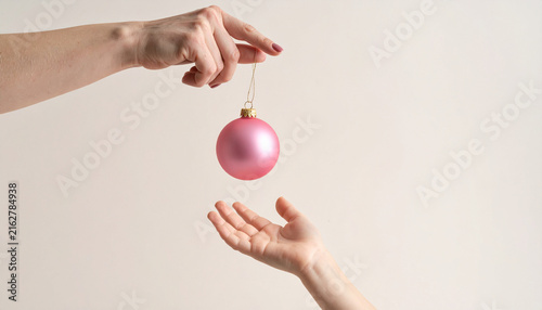 Hand Holding a Pink Bauble Above an Open Child Hand