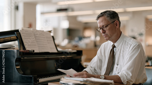Meteorologist reviewing barometric pressure readouts beside concert grand piano in hospital rehabilitation ward, piano tuner wrench resting on fallboard, aftermath of acoustic