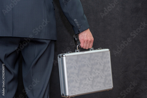 Konstfotografi Cropped businessman in dark suit holding silver briefcase beside body