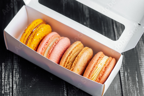 Bild auf Leinwand Assorted macarons in a white box on a dark wooden surface