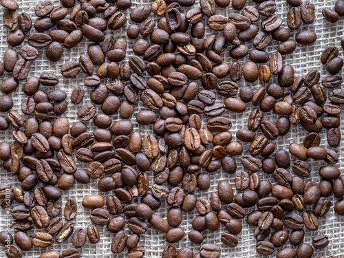 Kaffeebohnen locker verteilt auf einem Leinensack aus Jute als Hintergrund