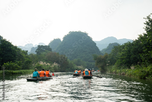Bild auf Leinwand Travelers take a traditional sampan boat tour through the scenic karst landscape of Vietnam