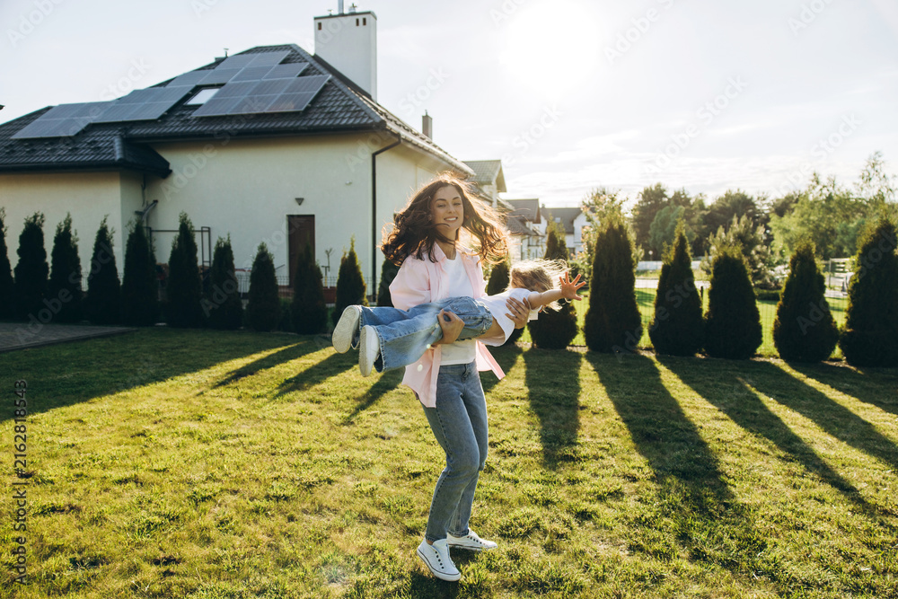 Obraz premium Mother and daughter playing outdoors in backyard with solar house