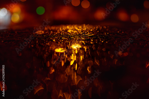 Fotografie Horizontal abstract macro view of golden christmas bokeh lights reflected on wet