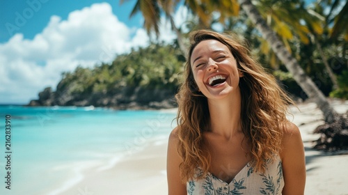Carefree young woman laughing with genuine joy on a tropical beach with crystal clear turquoise water, palm trees and white sand creating perfect summer vacation vibes