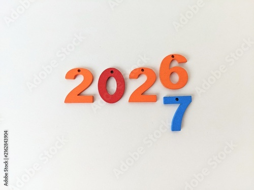Colorful numbers arranged on white background, highlighting 2026 with additional 7 symbolizing transition or connection to 2027. Happy new year concept.