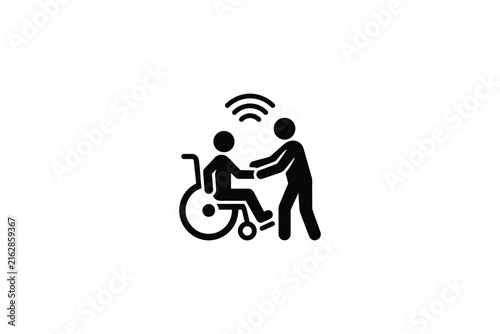 Black icon of caregiver assisting person in wheelchair with wireless signal symbol representing smart healthcare technology.