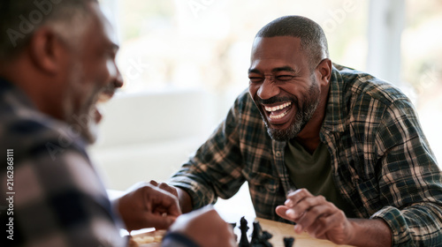 Two men laughing and playing chess at a bright modern table  