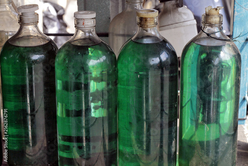 Green Liquid Bottles in Glass Containers on Shelf With Vintage Caps