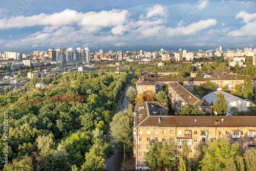 View of a city skyline with greenery and buildings during daytime under partially cloudy sky