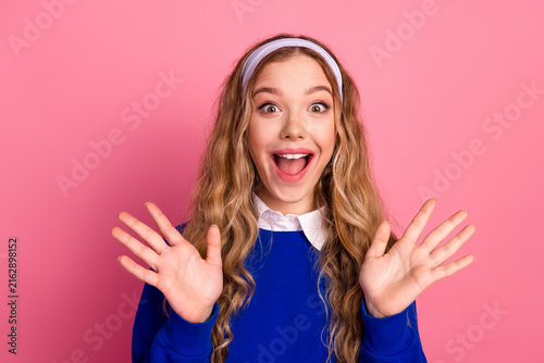 Happy young girl in blue sweater with headband smiling against pink background
