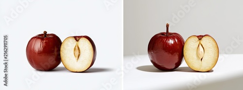 Two red apples, one whole and one halved, displayed on a white surface with a light grey background.