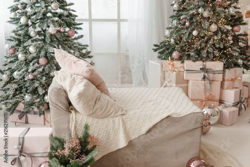 Quadro su tela Christmas interior with two decorated trees, glowing lights, wrapped presents, and cozy armchair