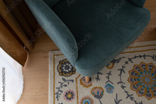 Close-up of a teal upholstered armchair and patterned rug in a modern interior