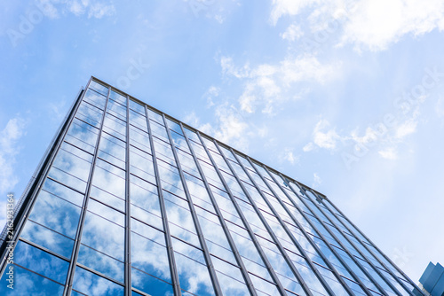 Low angle view of modern glass office building facade reflecting cloudy sky in Fukuoka, Japan