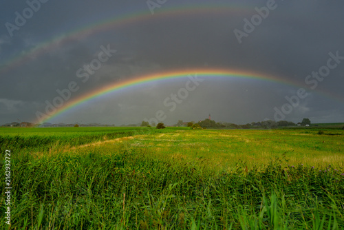 Canvas Print Rainbow arches across green field