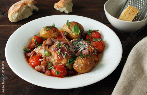 Baked chicken with roasted potatoes, cherry tomatoes, bacon and fresh basil, topped with parmesan cheese