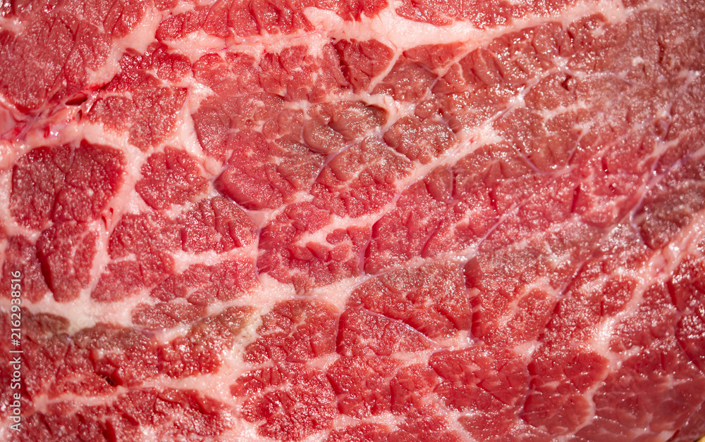 Obraz premium Raw beef texture with natural fat marbling. Raw beef macro background in pink tones. Detailed raw beef surface with muscle fibers. Close-up raw beef forms a food background.