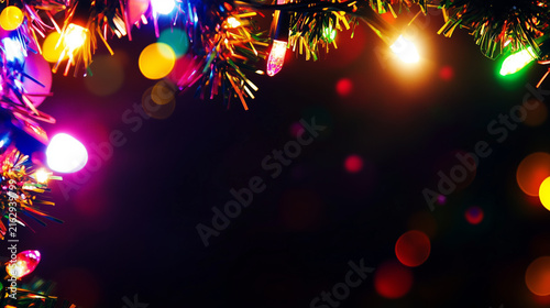 Christmas frame border with colorful string lights and glowing bokeh on dark background