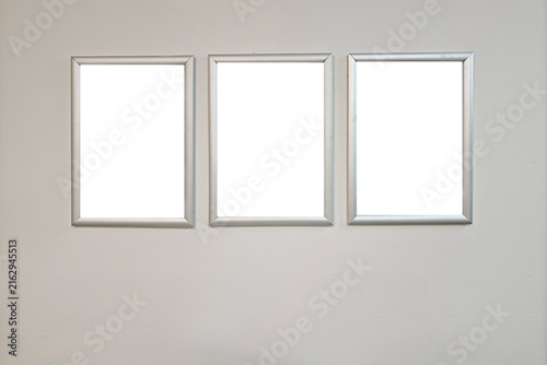 Cuadro en lienzo Three identical blank frames hanging horizontally on a neutral wall, offering co