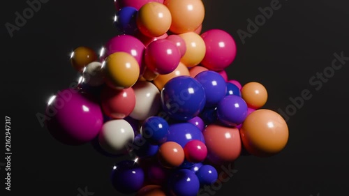 Colorful glossy spheres cluster and rotate against dark background