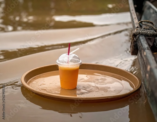 Refreshing Orange Drink in a Transparent Cup on a Tray Floating in Calm Water
