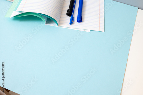 Notebook and blue pens on graph paper with large copy space for back to school designs