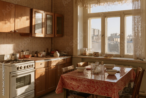 Cozy vintage kitchen in an old flat with wood cabinets, a large window, soft morning light, and a simple dining nook for warm home scenes.