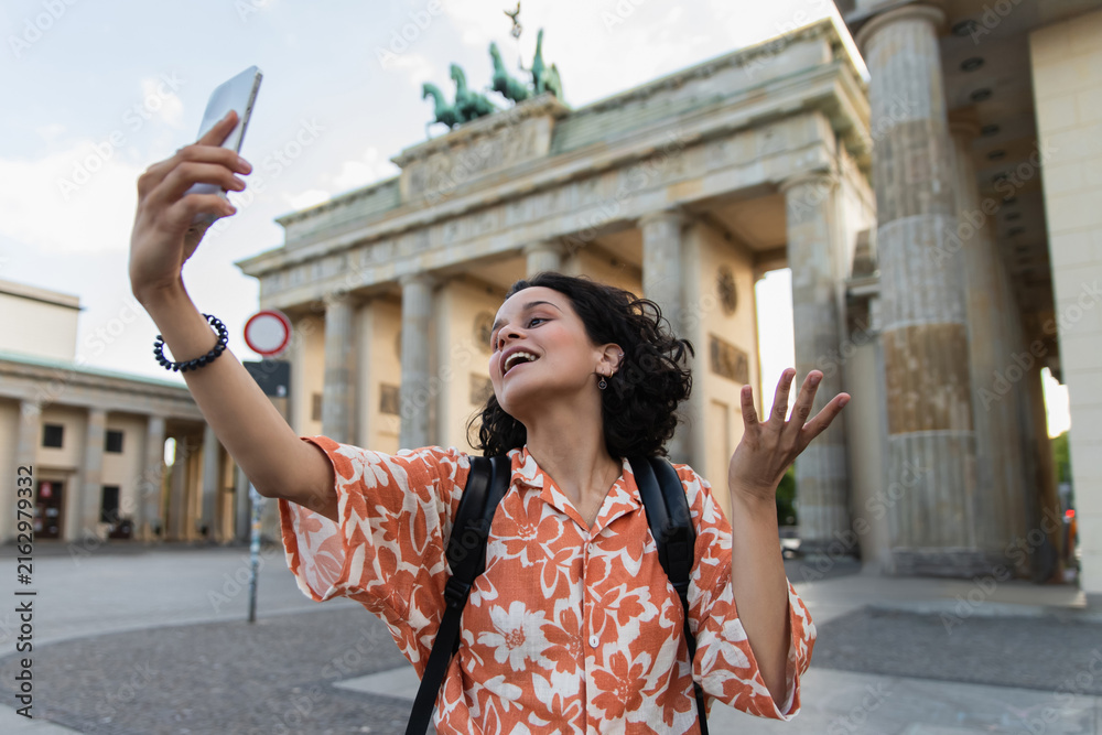 Naklejka premium Curly-haired traveler enjoying Berlin at the iconic Brandenburg Gate