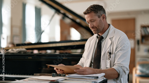Meteorologist reviewing barometric pressure readouts beside concert grand piano in hospital rehabilitation ward, piano tuner wrench resting on fallboard, aftermath of acoustic
