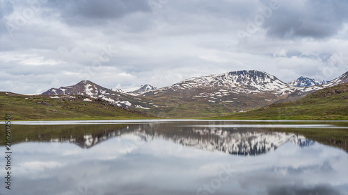 Canvas Print Scenic moody landscape view of snowcapped mountains with reflection in high-alti