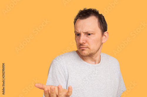 Bild auf Leinwand Man with confused expression holding out his hand on an orange background