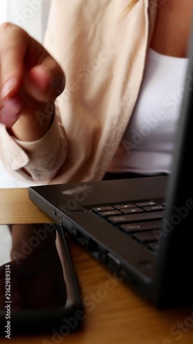 Close up woman switching from smartphone to laptop, remote work home office.