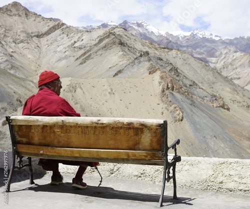 Foto Buddhist monk sitting on bench with Himalaya view in Ladakh, India