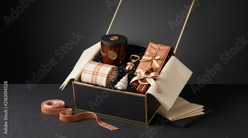 Gift box arrangement with candles, wrapped presents, and ribbon against a dark background