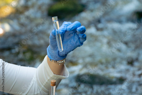 Foto person in blue gloves holding glass tube with water sample outdoors testing for