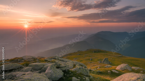 Sunrise Over Rocky Mountain Peaks With Hazy Valleys And Dramatic Clouds stone