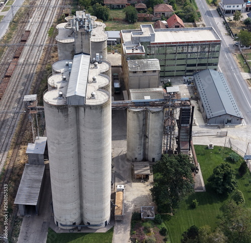 Aerial view of an industrial grain mill complex with tall concrete silos, warehouse buildings, railway tracks, and a truck parked on the premises in Smederevo, Podunavlje District, Serbia.