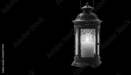 Vintage metal lantern with glowing candle isolated on black background