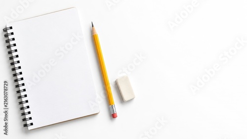 Blank spiral notebook with yellow pencil and eraser on white background with copy space