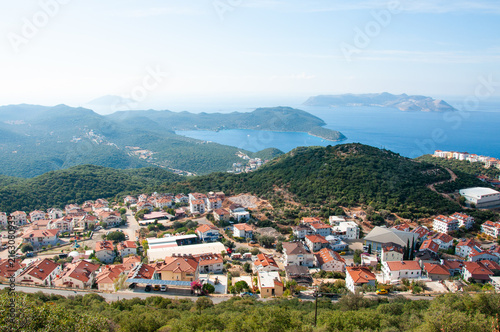 High angle panoramic view of Kas coastal resort town with red roof houses nestled near green hills and Mediterranean sea in Turkey