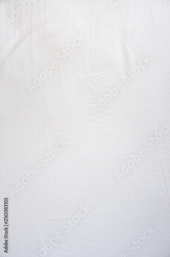 Close-up texture of soft white crumpled fabric, abstract wrinkled cotton sheet or linen cloth background