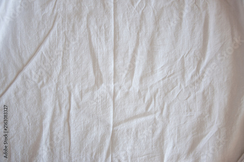 Close-up texture of heavily crumpled white linen fabric with folds and shadows, abstract wrinkled textile background