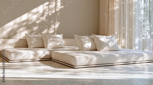 Minimalist lounge with white cushions and natural light casting leaf shadows on walls and floor