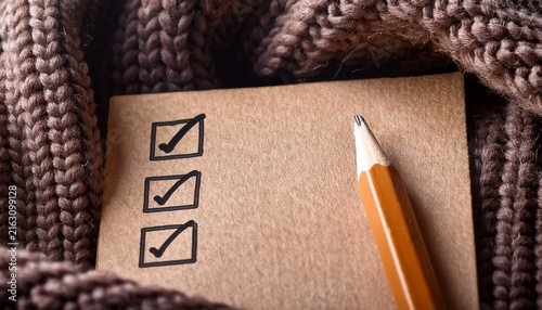 pencil marking a check box on kraft paper nestled in a knitted fabric